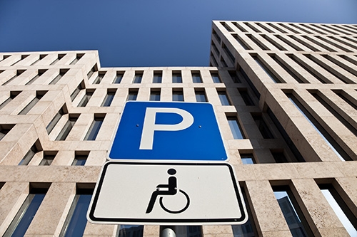 Panneau d'une place réservée aux personnes handicapées devant un building
